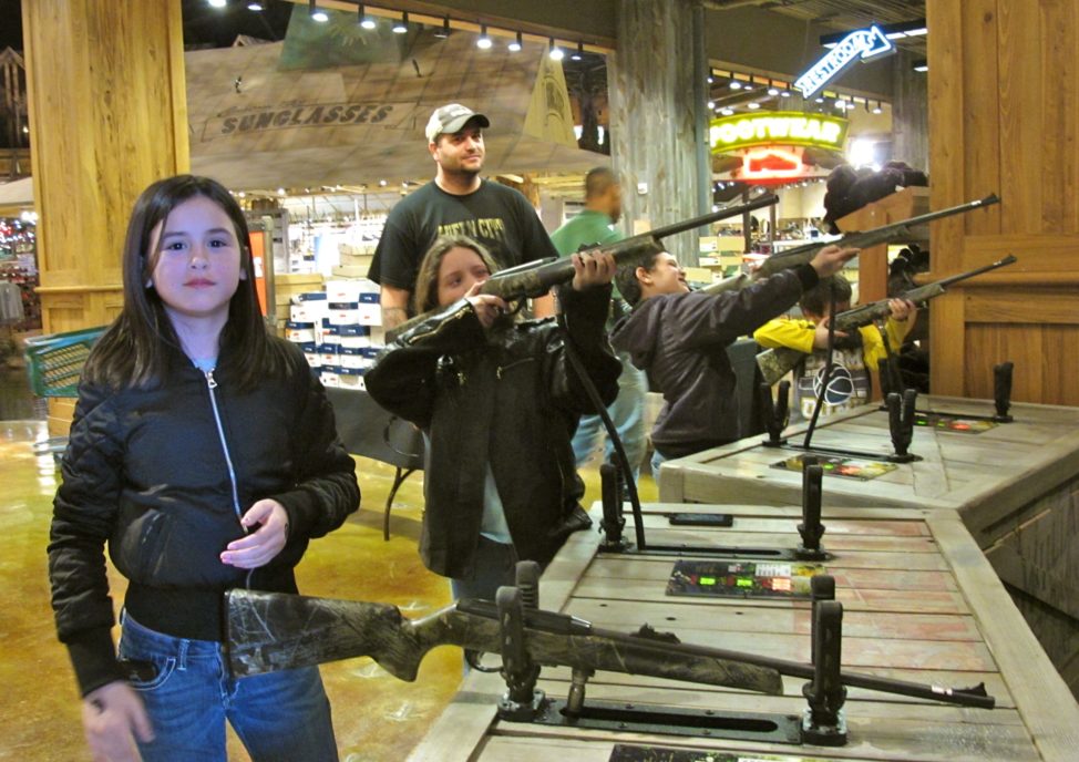 Chris Horsley of Texarkana, Texas, watches his children take aim at the shooting gallery in Bass Pro Shops at the Pyramid, a retail center in Memphis, Tennessee.  From left are Jordana, Christa, Corbin and Mason.  (C.Guensburg/VOA)   