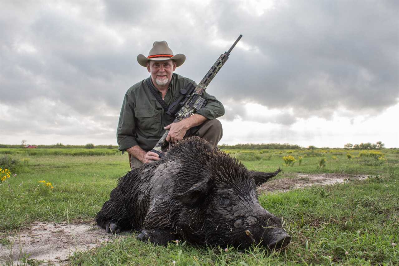 man standing next to dead wild pig